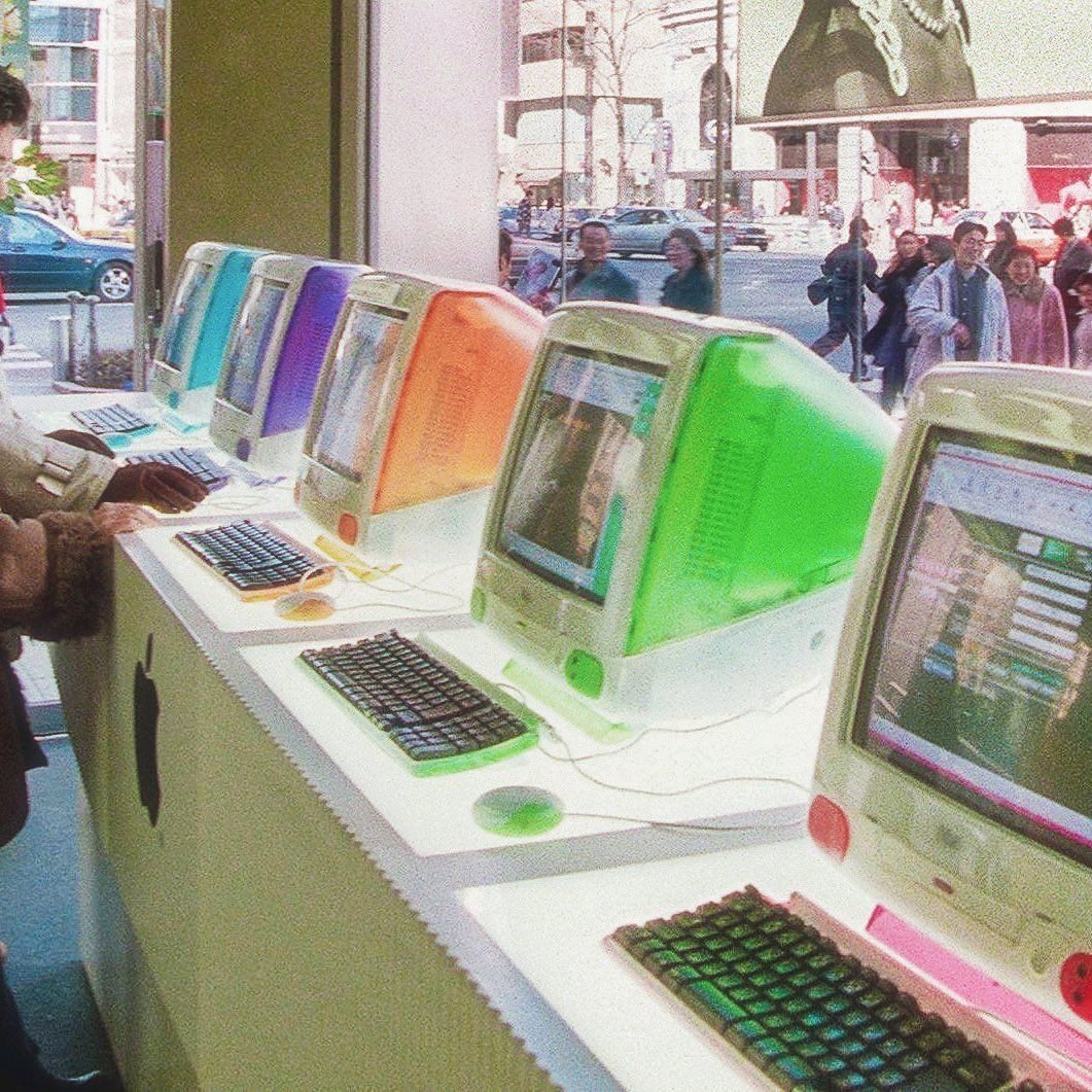 Fileira de computadores coloridos dos anos 1990 em uma vitrine